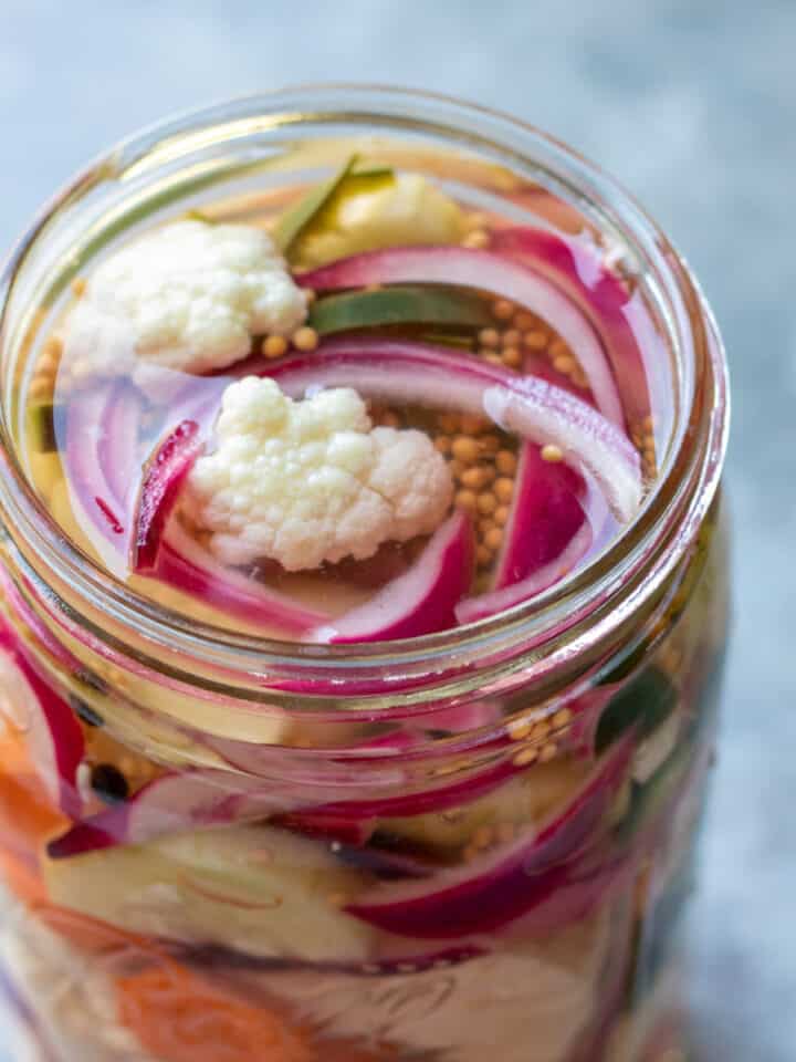 Looking into the top of a jar of colorful mixed pickled vegetables.