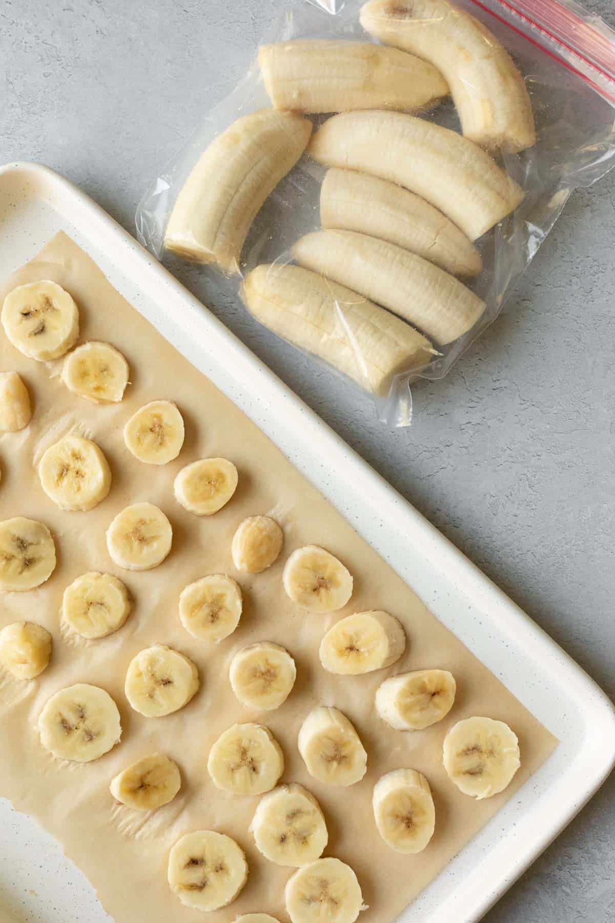 Arranging banana on a baking sheet for quick freezing, with whole bananas in a freezer bag.